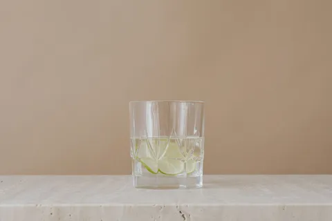 A clear glass of water on a light surface near a window with soft natural light