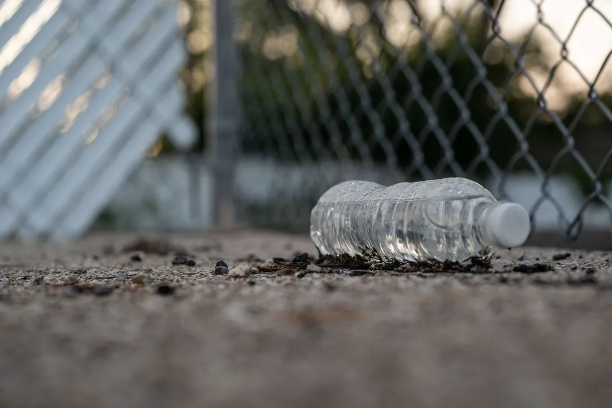 A single-use clear plastic water bottle sitting on a car dashboard in bright sunlight