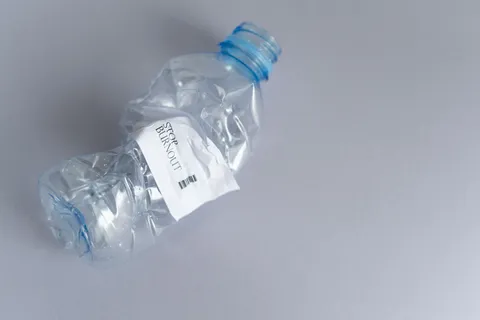 A single-use plastic water bottle on a plain surface in bright natural light