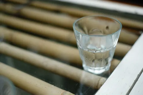 Close-up of clear water in a glass against soft natural light, suggesting invisible contaminants