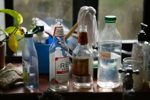 A clear glass of drinking water beside a plastic water bottle on a bright kitchen counter in natural light