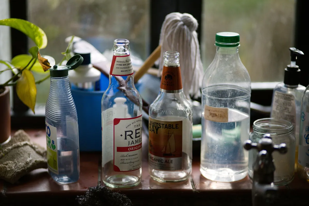 A clear glass of drinking water beside a plastic water bottle on a bright kitchen counter in natural light