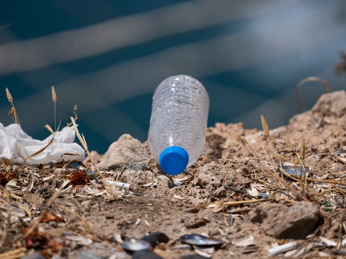 A single-use clear PET plastic water bottle on a light surface in natural daylight