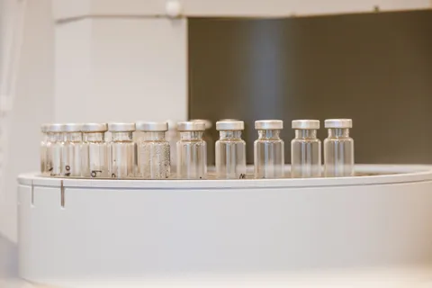 A researcher's gloved hand holding a clear vial against clean laboratory light