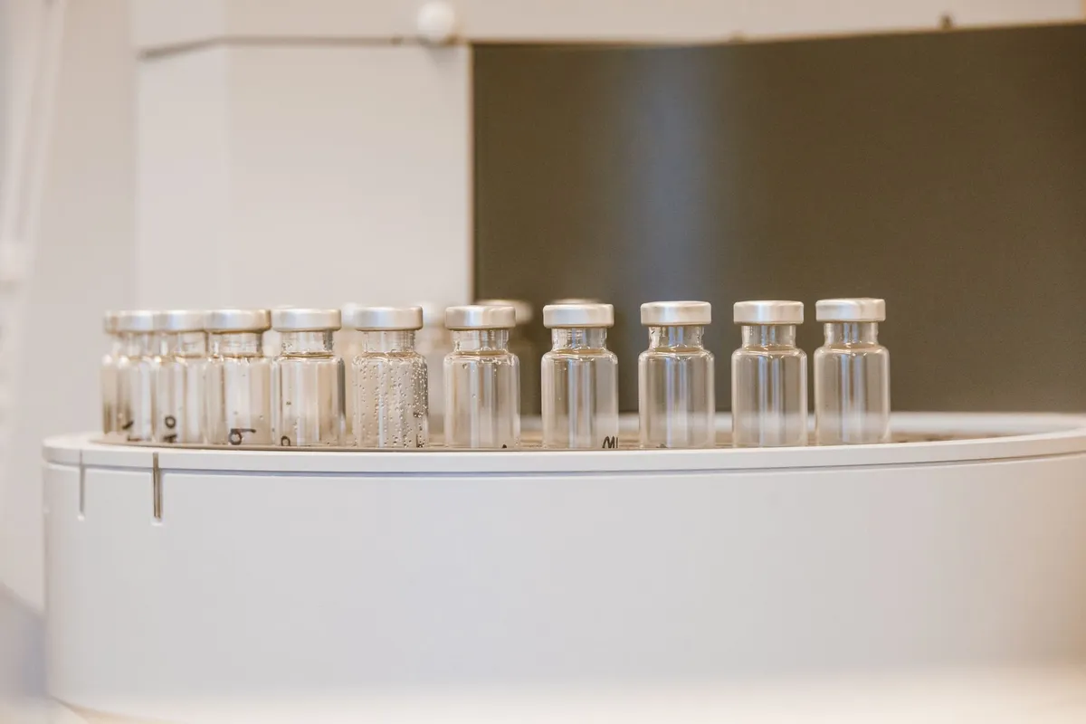 A researcher's gloved hand holding a clear vial against clean laboratory light