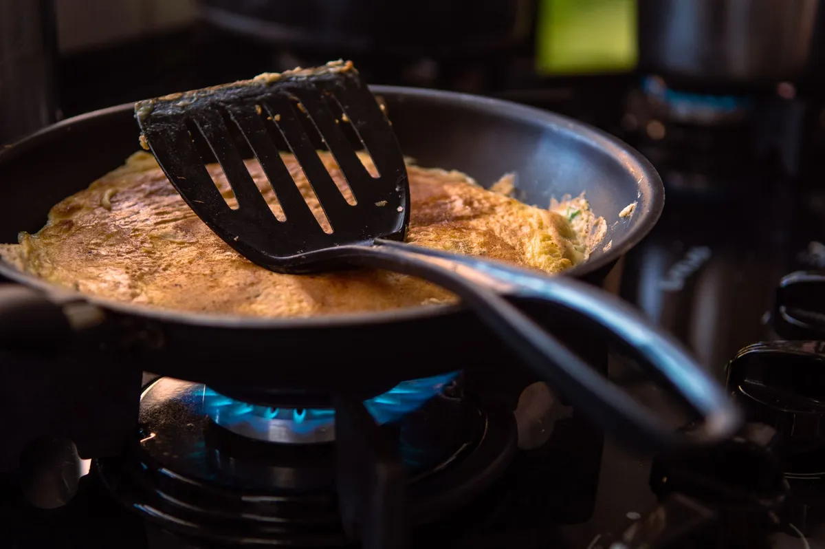 A non-stick coated frying pan on a stovetop in natural kitchen light
