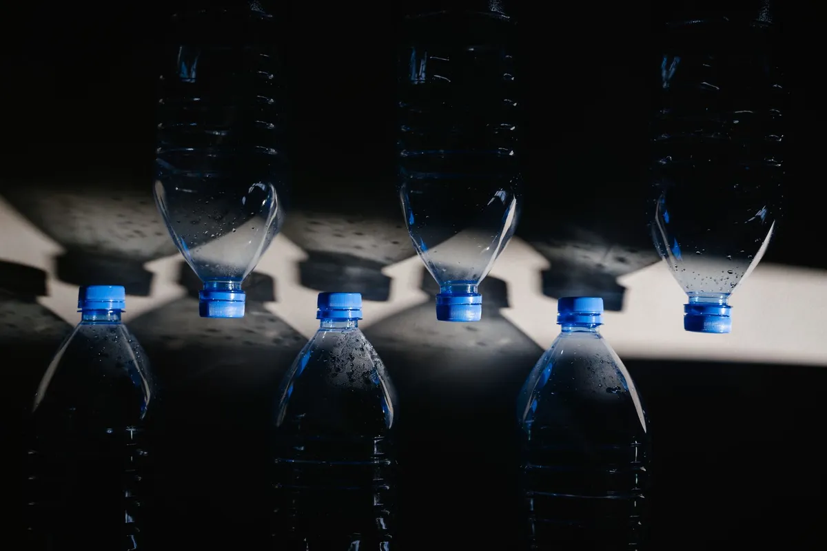 A single-use clear plastic water bottle on a plain surface in natural light