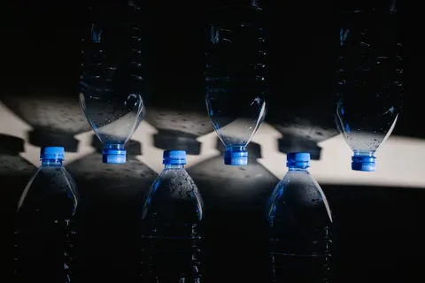 A single-use clear plastic water bottle on a plain surface in natural light