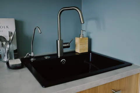 Clear water filling a drinking glass from a kitchen tap in natural daylight